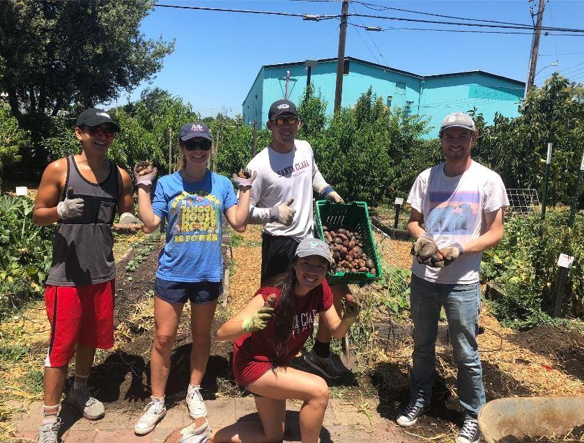 A group of Forge Garden Summer Interns holding baskets of vegetables and smiling