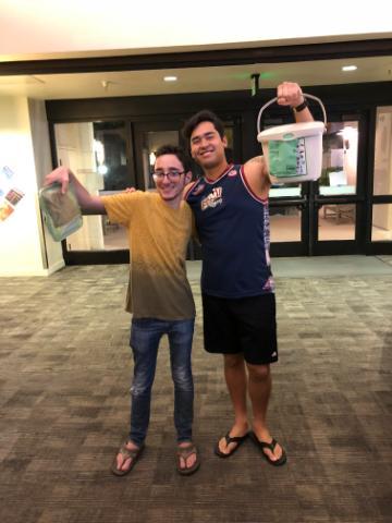 2 SCU students hold up their personal compost pails in the residence halls